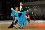 Lady in wheelchair wearing blue ball gown, dancing with man in suit