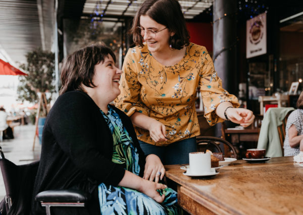 Two young women at a cafe chatting and laughing