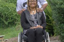 Teremoana sitting in her wheelchair and Aukilani standing behind her with his hands on Teremoana's shoulders