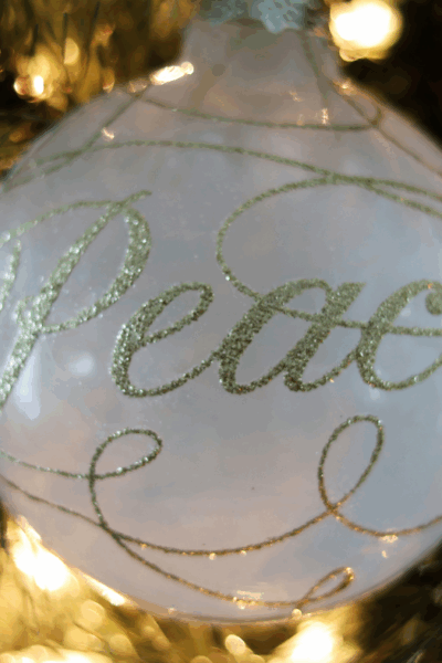 Christmas tree decoration with the word "peace" printed in gold on it.