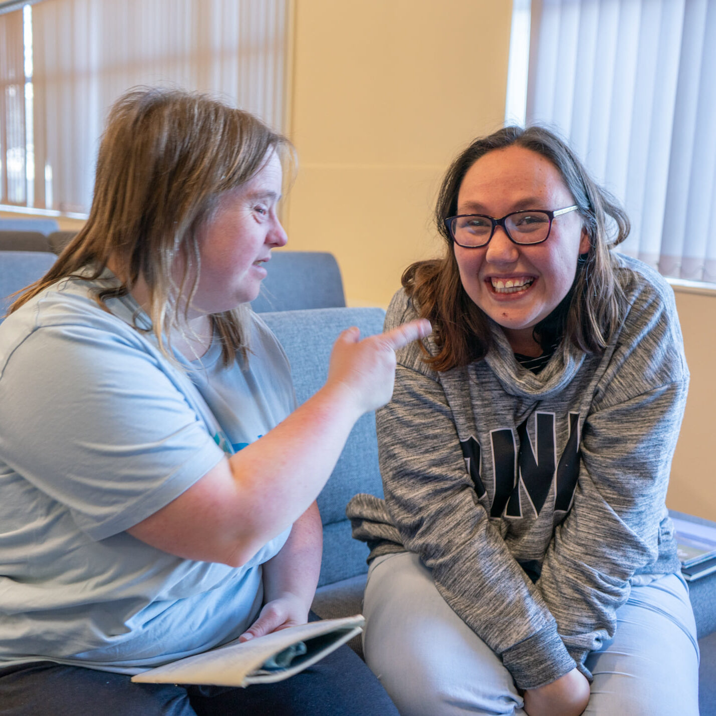 Two young ladies wearing grey smiling