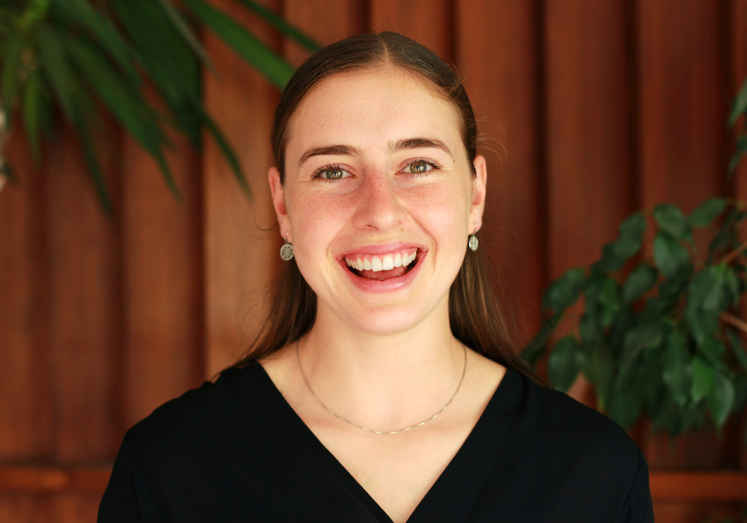 Ella wears a black shirt and silver string necklace.