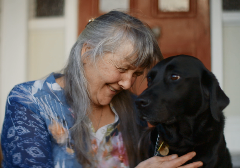 One of the leaders of the Northland CFFD group sits on a deck outside with a black labrador