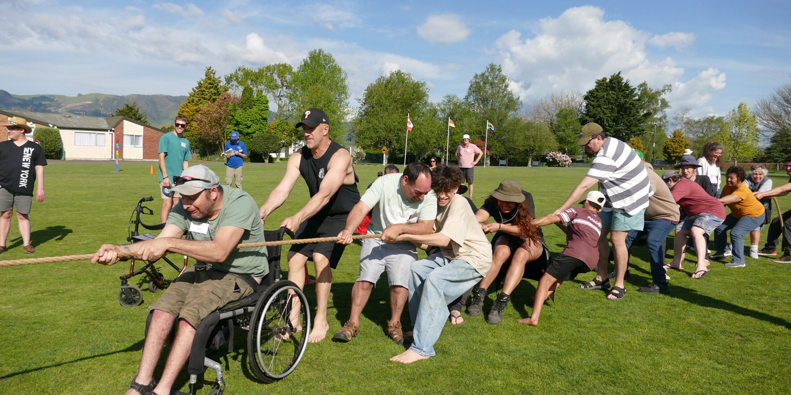 Large group of people playing tug of war on a field at National Camp